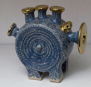 Blå dantasifigur formad som en cylinder med guld trumpetertrumpeter och fyra ben